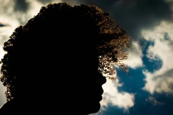 Imagem colorida mostra sombra de pessoa de cabelos crespos, com céu ao fundo - Metrópoles