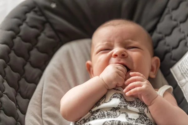Bebê chorando com a mão na boca