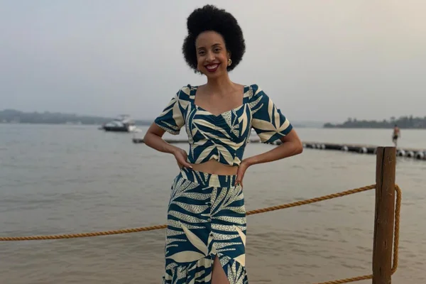 Foto colorida de mulher com roupa de listras rente ao mar - Metrópoles