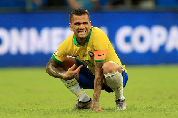 Dani Alves agachado com a camisa do Brasil