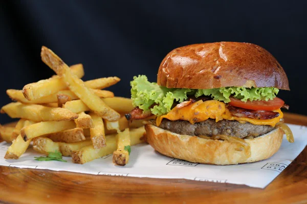 Foto de hambúrguer com carne e salada e batatas fritas ao lado