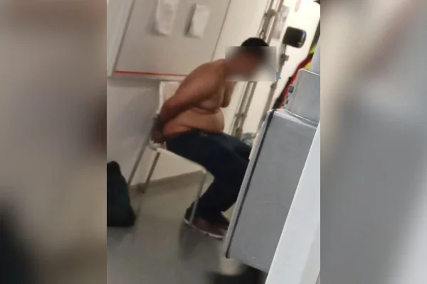 Imagem colorida mostra homem algemado sentado em banco. Ele é acusado de assédio sexual em trem da CPTM - Metrópoles