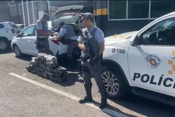 Imagem colorida mostra policiais com pacotes de skunk apreendidos em rodovia no interior de São Paulo - Metrópoles