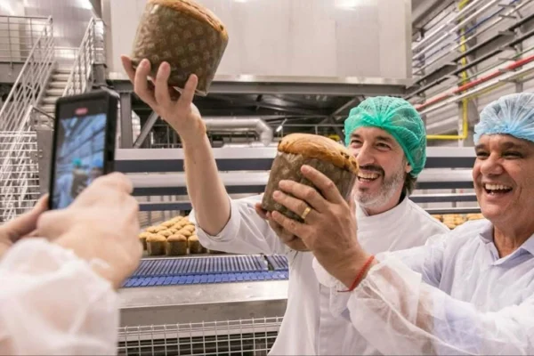 CEO da Cacau Show, Alê Costa, segurando panetone ao lado de funcionário