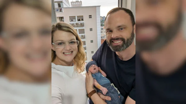 Foto colorida de Cheri e Chris Phillips com o bebê Greyson casal dos EUA - Metrópoles