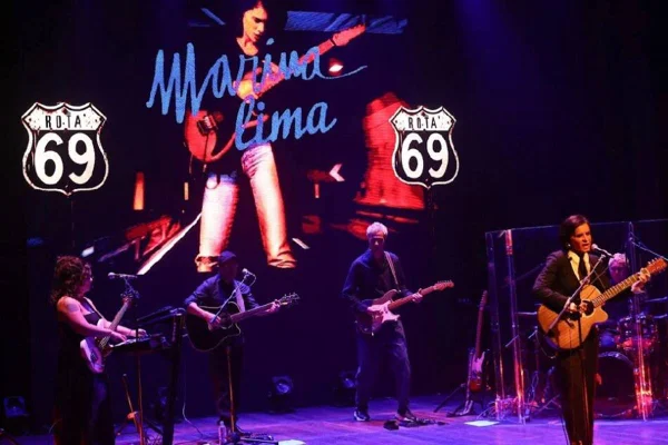 Na imagem colorida, Marina Lima canta em microfone e toca violão, em imagem de divulgação de nova turnê - Metrópoles