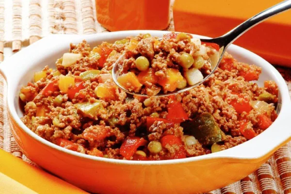 Imagem colorida de refogadinho de carne dentro de panela laranja