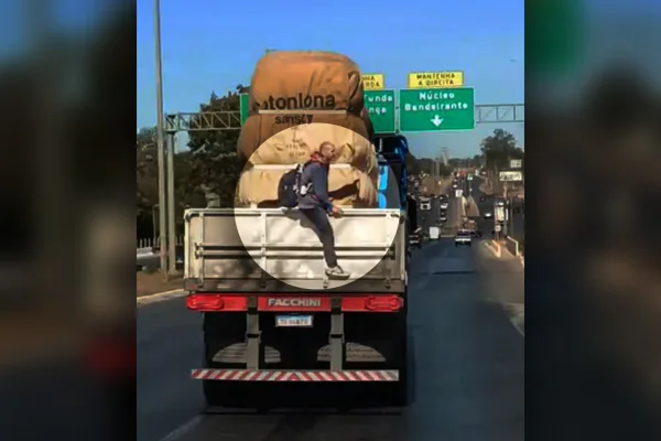 Foto colorida homem pega carona em caminhão