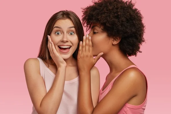 Duas amigas fofocando, mulheres falando uma no ouvido da outra