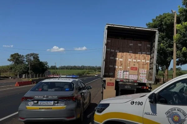 Imagens coloridas mostram carreta com caixas de maços de cigarros contrabandeados escondida e viaturas da Polícia Militar Rodoviária