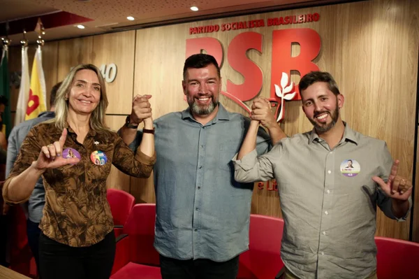 Mulher e dois homens lado a lado segurando as mãos e sorrindo