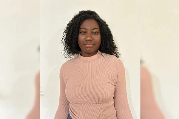 Imagem colorida de uma jovem negra, com cabelo cacheado, vestindo uma blusa de manga longa salmão