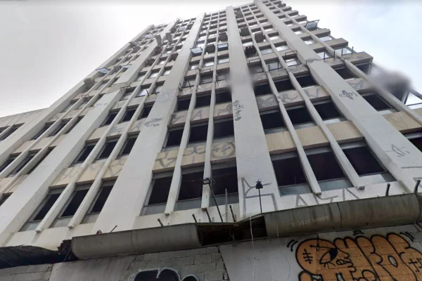 Imagem colorida de prédio no centro de SP. Imagem é de baixo para cima. Há pichação e grafite na fachada - Metrópoles