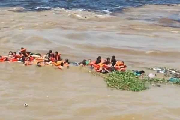 Imagem colorida mostra pessoas na água, onde lancha naufragou em Manaus - Metrópoles