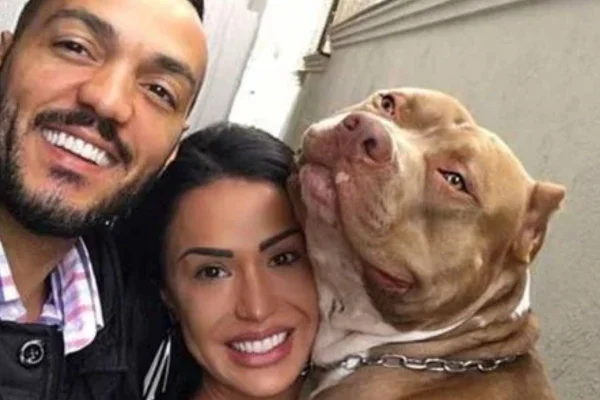 Foto colorida de um casal com um cachorro - Metrópoles