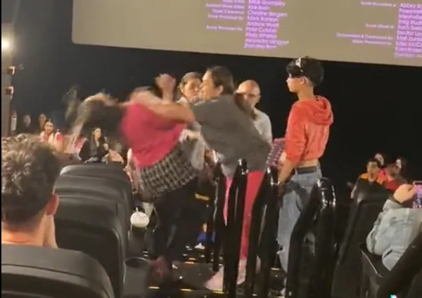 Mulher com blusa rosa é empurrada por mulher com blusa cinza em escada de sala de cinema - Metrópoles