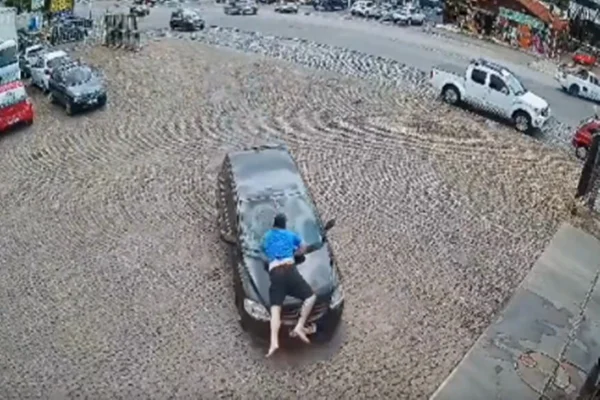 Imagem colorida de homem sendo levado em capoô de carro - Metrópoles
