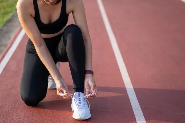 Close de uma corredora esportiva fitness se preparando para correr ao ar livre - Metrópoles