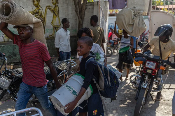 Imagem de pessoas fugindo do Haiti com seus pertences pessoais devido à onda de violência em 2024