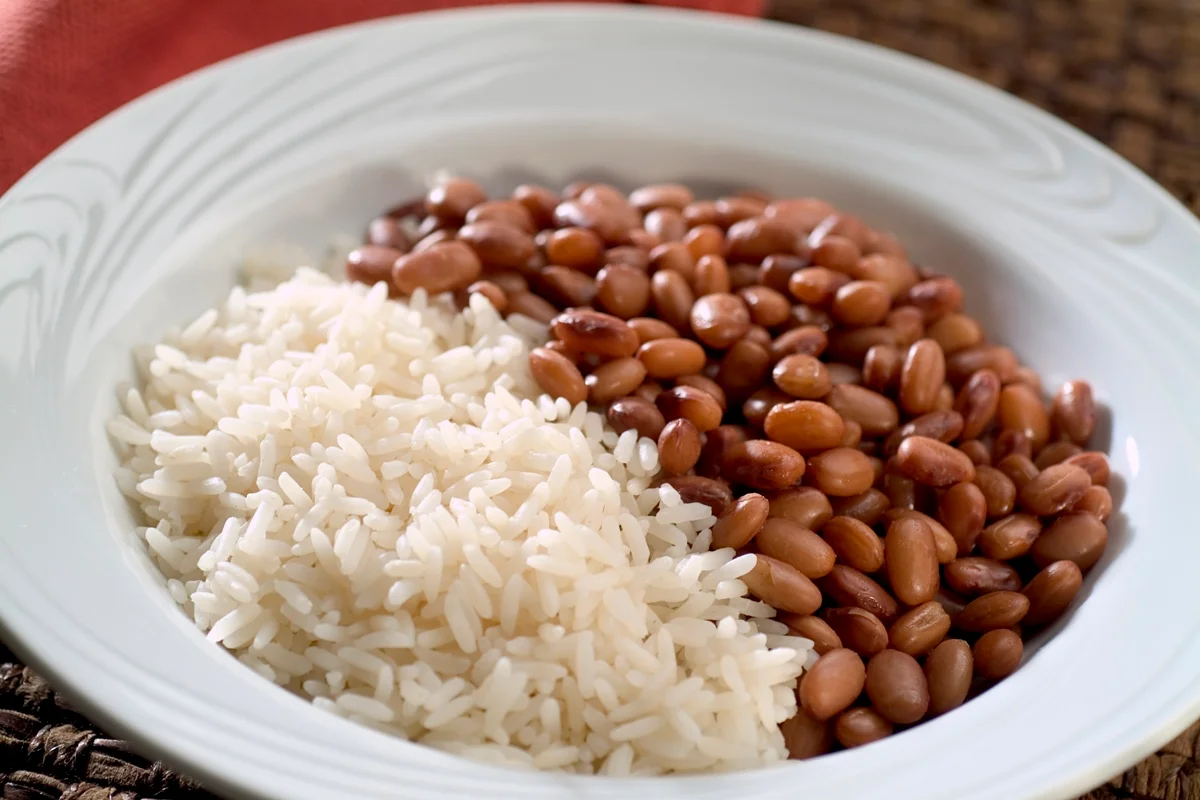 Almoço típico brasileiro, prato de arroz e feijão marrom.