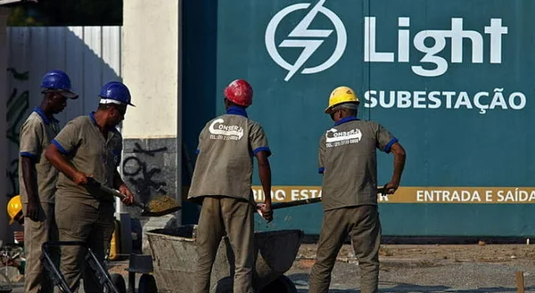 Imagem com funcionários da Light trabalhando. Ai fundo, logotipo da empresa em uma parede verde.