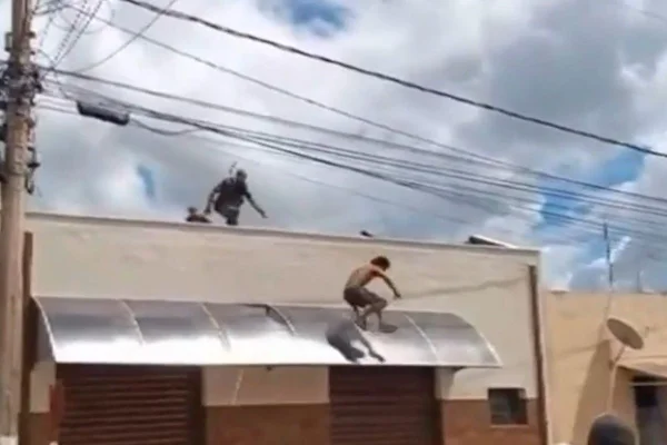 Imagem colorida mostra homem pulando de um telhado para fugir de um policial militar (PM) que o perseguia - Metrópoles