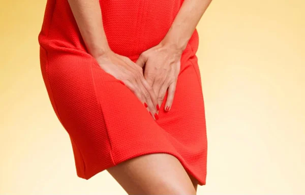 Imagem de mulher com vestido vermelho com as mãos na frente da bexiga - Metrópoles