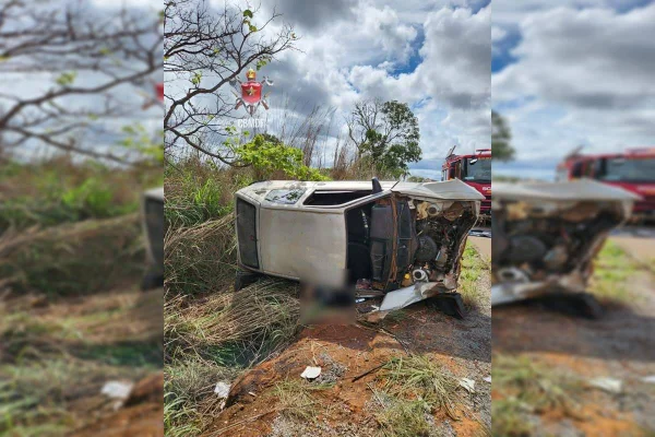 Carro cinza tombado lateralmente em barranco. Foto colorida