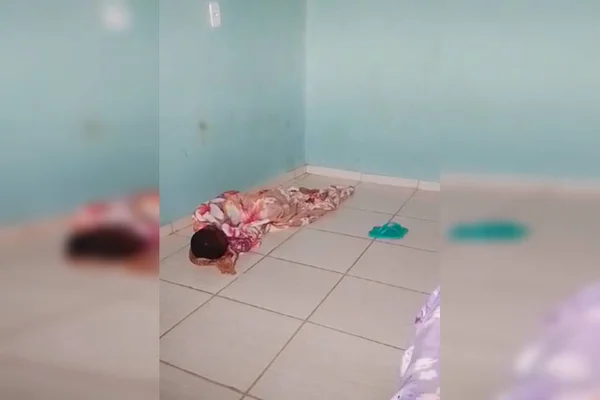 Foto colorida mostrando criança dentro de casa deitada no chão com coberta. Menino maltratado pela madrasta - Metrópoles