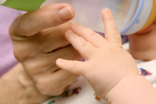 Foto colorida de homem dando mamadeira para bebê. Imagem ilustrativa - Metrópoles