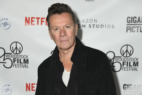 Imagem colorida de Larry Mullen Jr. usando roupa preta em tapete vermelho - Metrópoles