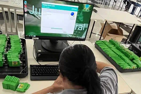 Fotografia colorida de mulher sentada em frente a computador