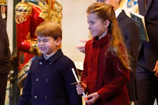 Foto colorida de duas crianças, sendo um menino com casaco azul-escuro e uma menina com casco vermelho, segurando uma vela - Metrópoles