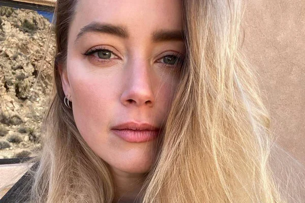 foto colorida do rosto de Amber Heard, mulher branca e loira de olhos claros olhando séria - metrópoles