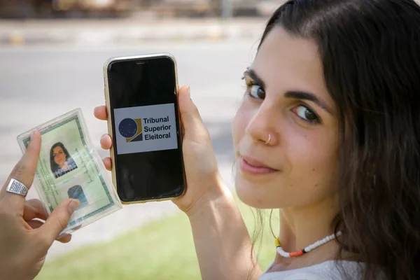 menina segurando o celular e a identidade