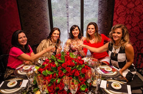 Mulheres brindando em mesa decorada