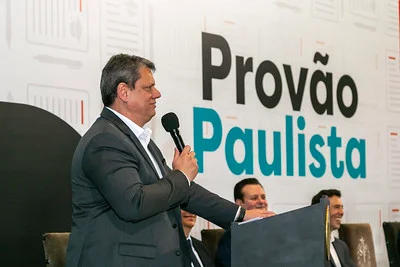 Imagem colorida de Tarcísio de Freitas de perfil segurando um microfone - Metrópoles