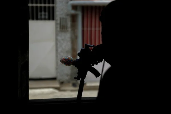 Imagem colorida, pessoa segurando arma de bolinhas - Metrópoles