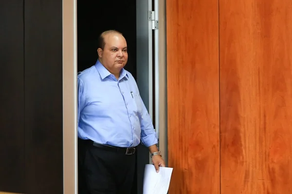 Foto de um homem saindo de uma porta entreaberta