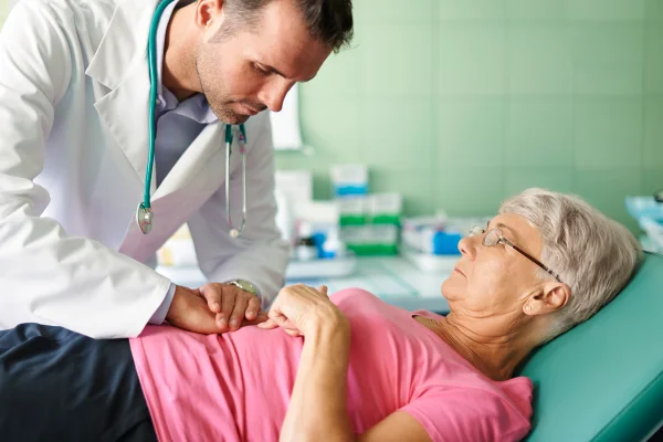 Foto colorida de idosa se consultando com médico - Gastroenterologistas explicam os principais sintomas de pancreatite - Metrópoles