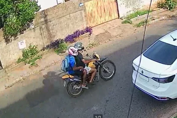 Imagem colorida, dois homens em cima da moto ao lado de um carro branco - Metrópoles