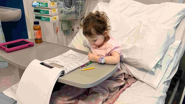 Foto mostra Grace Tudor pintando um desenho em uma cama de hospital após o diagnóstico do câncer