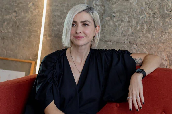 Thais Farage sentada no sofá com look preto