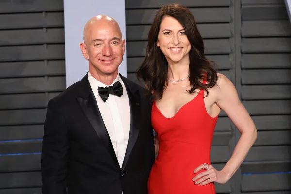 Foto colorida. Homem branco e careca está usando um terno preto. Ao lado dele, está a ex-esposa, uma mulher branca, de cabelos pretos lisos usando um vestido vermelho - Metrópoles