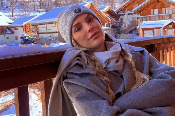 Imagem colorida de Rafa Brites posando para a foto a frente de um fundo com uma cabena coberta com neve - Metrópoles