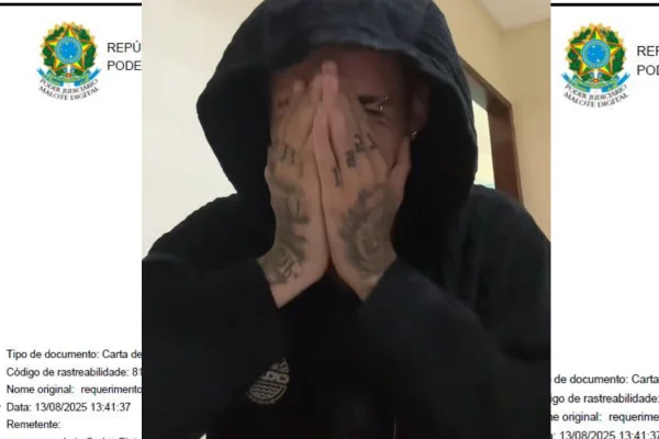 Homem branco tapa rosto com as mãos, tatuadas, com a cabeça coberta por capuz de moletom preto - Metrópoles