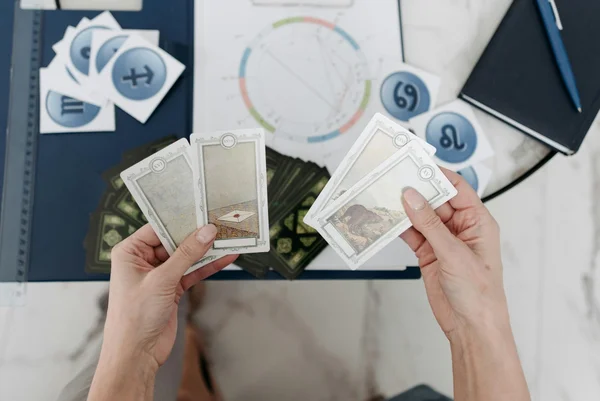 mãos segurando cartas de signos com símbolos de signos