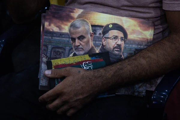 Imagem colorida mostra homem segurando uma fotos de Qasem Soleimani e Fuad Shukr - Metrópoles