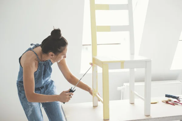 mulher pintando móvel de madeira