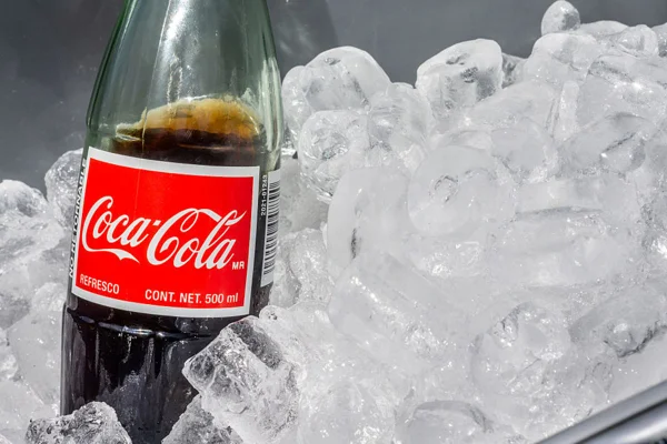 Imagem de garrafa de Coca-Cola mergulhada em caixa com gelo - Metrópoles